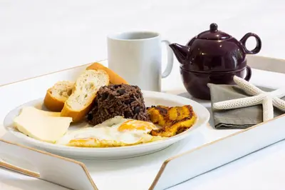 a plate of food with eggs and bread and a cup at Pumilio Mountain & Ocean Hotel in Jacó