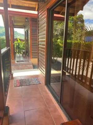 a screened porch with sliding glass doors and a person on the balcony at Clusia Lodge in El Copey