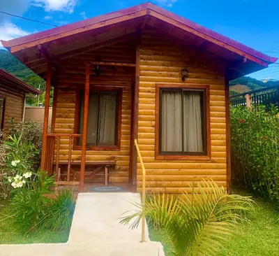 a wooden cabin with a porch and two windows at Clusia Lodge in El Copey