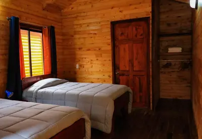 a bedroom with two beds in a log cabin at Clusia Lodge in El Copey