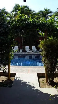a swimming pool with two chairs and trees in front at Hotel El Paraiso Escondido - Costa Rica in Jacó