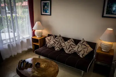 a living room with a couch with pillows on it at Villa Creole in Jacó