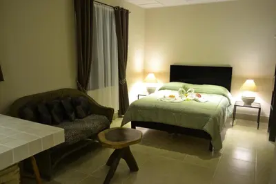 a bedroom with a bed and a chair and a couch at Villa Creole in Jacó