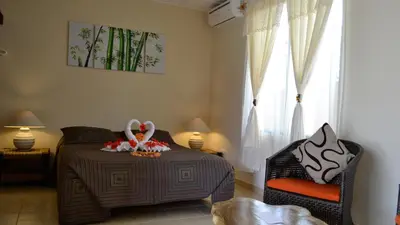 a bedroom with a bed and a chair and a window at Villa Creole in Jacó