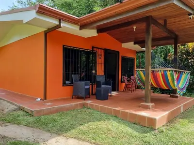 an orange house with a deck with chairs and a hammock at casa de playa Paraíso terrenal in San Juanillo