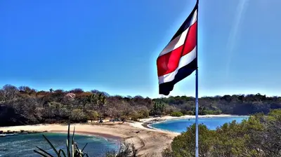 a flag on a pole next to a beach at casa de playa Paraíso terrenal in San Juanillo