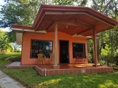 a small orange house with a porch and chairs at casa de playa Paraíso terrenal in San Juanillo