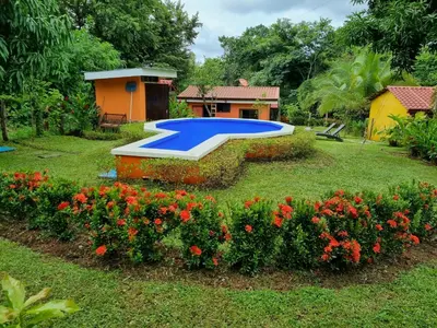 a large pool in a yard with flowers at casa de playa Paraíso terrenal in San Juanillo