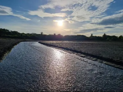 a body of water with the sun in the sky at casa de playa Paraíso terrenal in San Juanillo