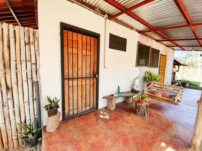 an open door of a house with plants and a bench at Casa Ital-Tico, Playa Negra in Playa Negra