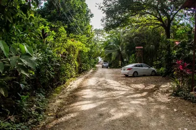 a dirt road with a white car parked on the side at Plaza Royal Apartments in Santa Teresa Beach