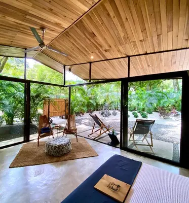 a room with glass doors and chairs and a table at Villas Kalei in Playa Grande