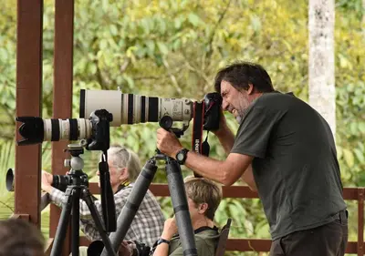 a man looking through a camera on a tripod at La Laguna del Lagarto Eco-Lodge in Pital
