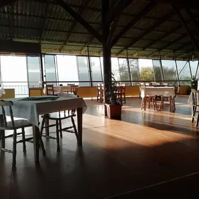 a group of tables and chairs in a room with windows at Pochotel in Turrialba