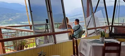 a man and woman sitting in a restaurant looking out the window at Pochotel in Turrialba