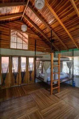 a room with two bunk beds and a wooden ceiling at Salty Enthusiasts Share House & Villas in Santa Teresa Beach