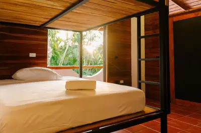 a bedroom with a large bed with a large window at Salty Enthusiasts Share House & Villas in Santa Teresa Beach