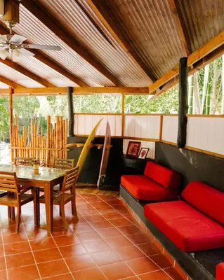 a living room with a red couch and a table at Salty Enthusiasts Share House & Villas in Santa Teresa Beach