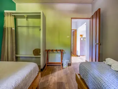 a bedroom with two beds and a door to a hallway at Cantos Del Bosque in Monteverde Costa Rica