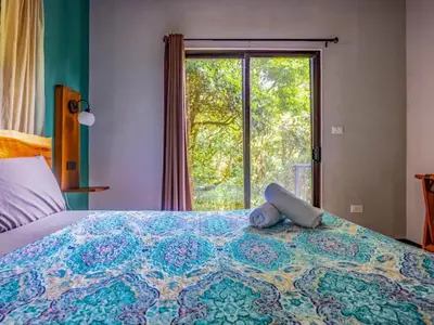 a bedroom with a large bed with a large window at Cantos Del Bosque in Monteverde Costa Rica