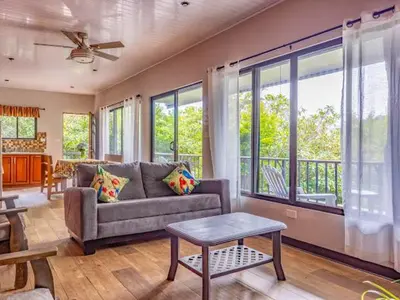 a living room with a couch and large windows at Cantos Del Bosque in Monteverde Costa Rica