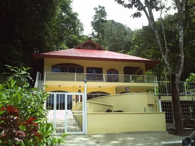 a yellow house with a gate in front of it at Villa Vista Verde Ground Floor Home, Save Hundreds on your trip, Reduced Prices on Tours in Quepos