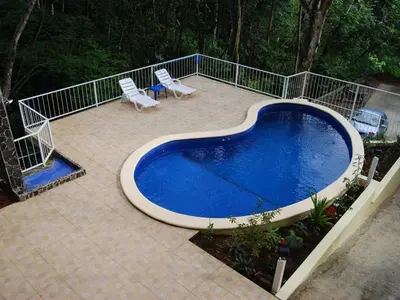 a swimming pool on a patio with two chairs at Villa Vista Verde Ground Floor Home, Save Hundreds on your trip, Reduced Prices on Tours in Quepos