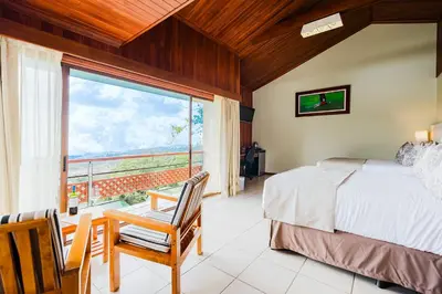 a bedroom with a bed and a large window at Ficus Sunset Suites in Monteverde Costa Rica