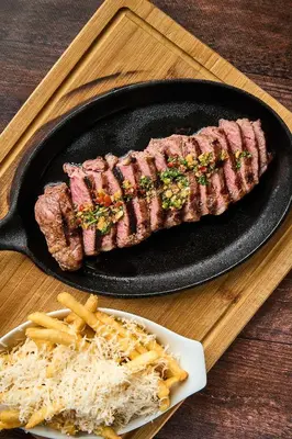 a piece of steak on a skillet with french fries at Ficus Sunset Suites in Monteverde Costa Rica