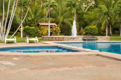 a swimming pool with a fountain in a park at Hotel Guanacaste Lodge in Playa Flamingo