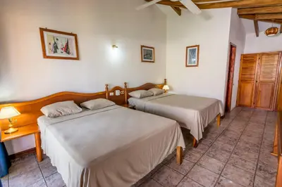 a bedroom with two beds and a table with a lamp at Hotel Guanacaste Lodge in Playa Flamingo