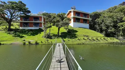 a bridge over a body of water with a building at Burbi Lake Lodge Monteverde in Monteverde Costa Rica