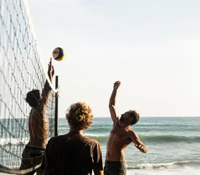 a group of men playing volleyball on the beach at La Posada - Hostel in Santa Teresa Beach