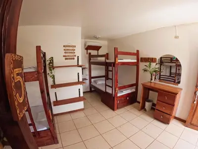 a room with several bunk beds and a desk at La Posada - Hostel in Santa Teresa Beach