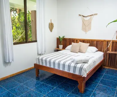 a bedroom with a bed in a room with blue tiles at La Posada - Hostel in Santa Teresa Beach