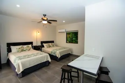 a hotel room with two beds and a table at Hotel Green Jacó in Jacó