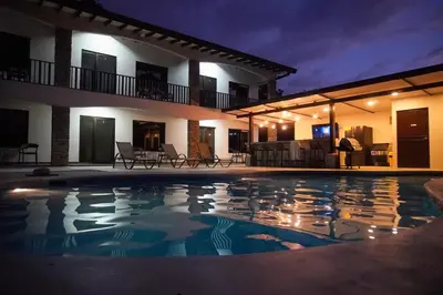 a swimming pool in front of a house at night at Hotel Green Jacó in Jacó