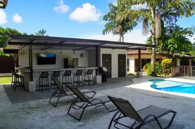 a patio with a bar and chairs next to a pool at Hotel Green Jacó in Jacó