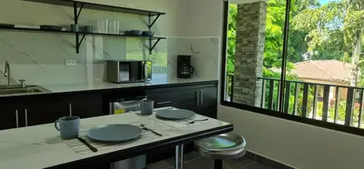 a kitchen with a table with plates and a microwave at Hotel Green Jacó in Jacó