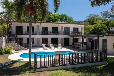 a villa with a swimming pool and a house at Hotel Green Jacó in Jacó