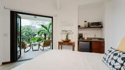 a bedroom with a bed and a kitchen with a balcony at Tulemar in Manuel Antonio