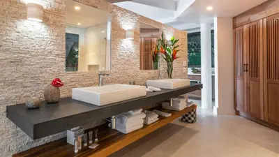 a bathroom with two sinks and a brick wall at Tulemar in Manuel Antonio