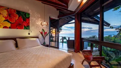 a bedroom with a bed and a large window at Tulemar in Manuel Antonio