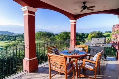 a porch with a table and chairs and a grill at Designer Penthouse - Bougainvillea - Reserva Conchal Golf Resortl in Playa Conchal