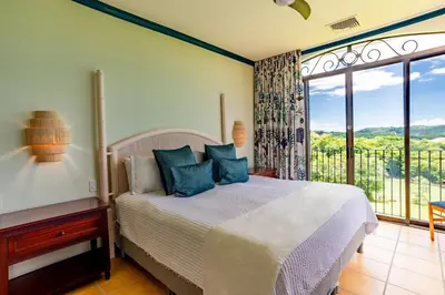 a bedroom with a bed and a large window at Designer Penthouse - Bougainvillea - Reserva Conchal Golf Resortl in Playa Conchal