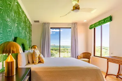 a bedroom with a bed and a large window at Designer Penthouse - Bougainvillea - Reserva Conchal Golf Resortl in Playa Conchal