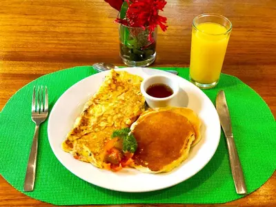 a plate of breakfast food with omelets and a glass of orange juice at Arenal Oasis Eco Lodge & Wildlife Refuge in Fortuna