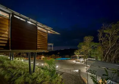 a building with a bench and a swimming pool at night at Pacific Kalokairi - Adults Only in Tamarindo