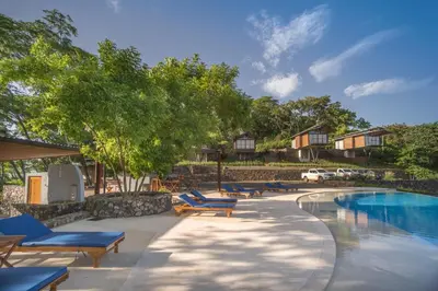a swimming pool with lounge chairs and a resort at Pacific Kalokairi - Adults Only in Tamarindo
