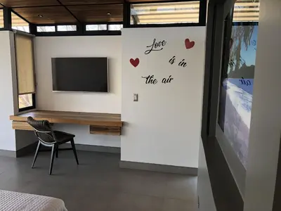 a room with a tv and a chair and a desk at Pacific Kalokairi - Adults Only in Tamarindo